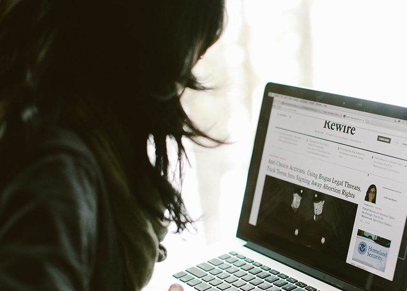 Image of woman looking at the redesigned Rewire.News website on a laptop