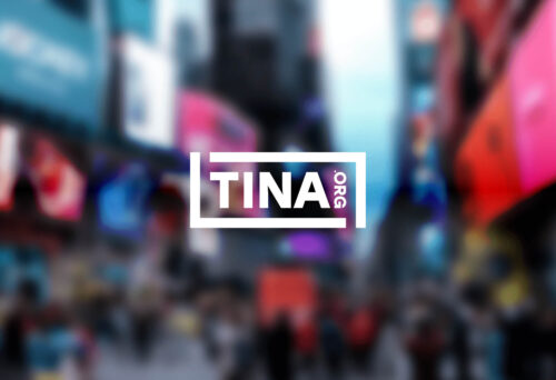Blurry image of Times Square in New York with a white TINA logo centered on top of the image.