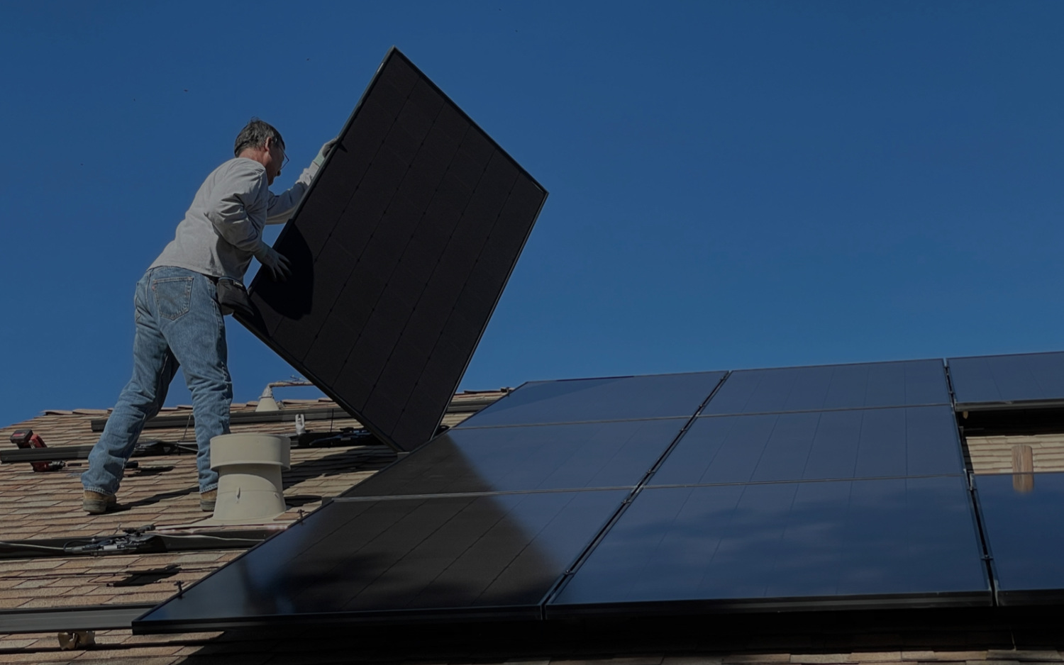 Worker installing solar panel on a roof