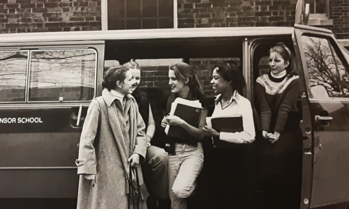 Historic sepia photo of diverse Winsor School girls standing in front of a van chatting, laughing, and holding books, likely the 1960s or 70s