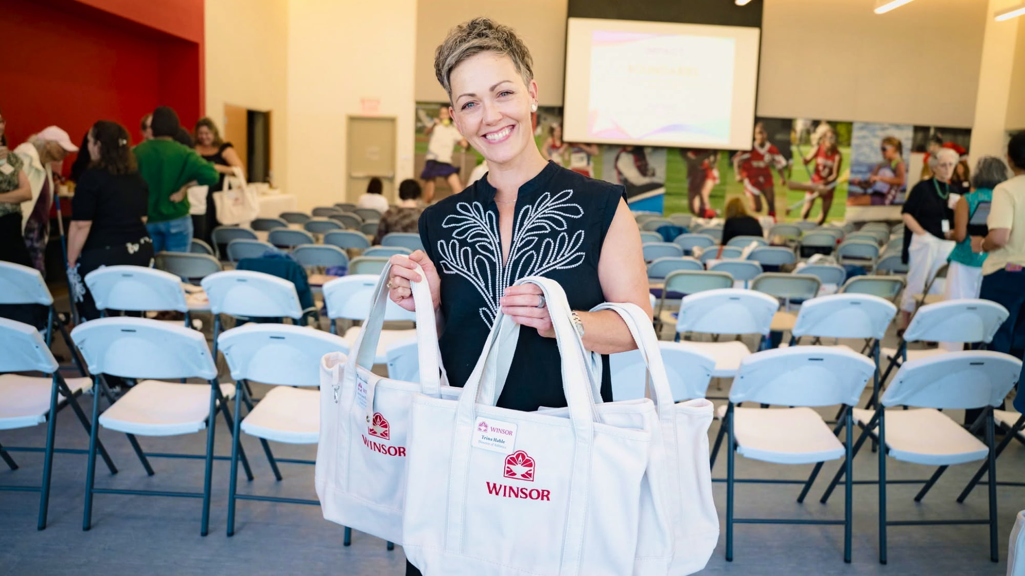 Photo of Winsor's Chief Communications Officer, Janelle, holding totes with Winsor's new logo embroidered